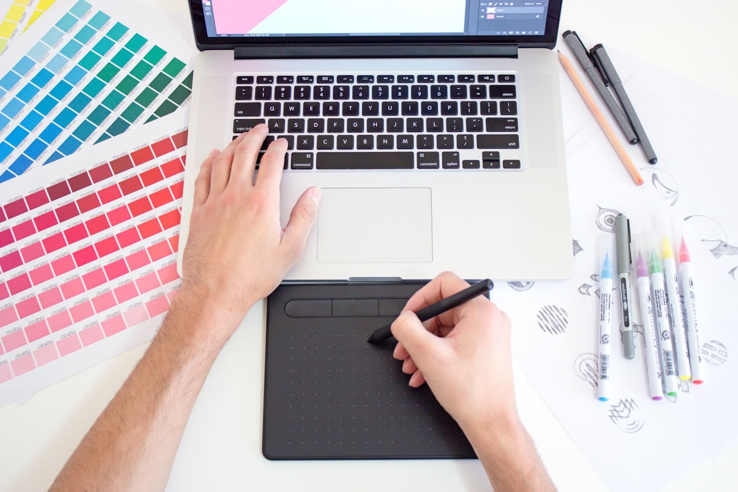 Designer workspace with laptop, drawing tablet, and color swatches